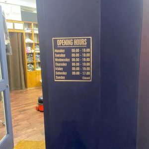 Business opening hours sign displayed on a wall inside a shop in West London
