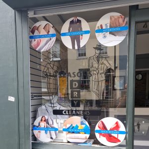 Shopfront window graphics for dry cleaners in West London, displaying services like dry cleaning, shirt laundry, alterations, and more.